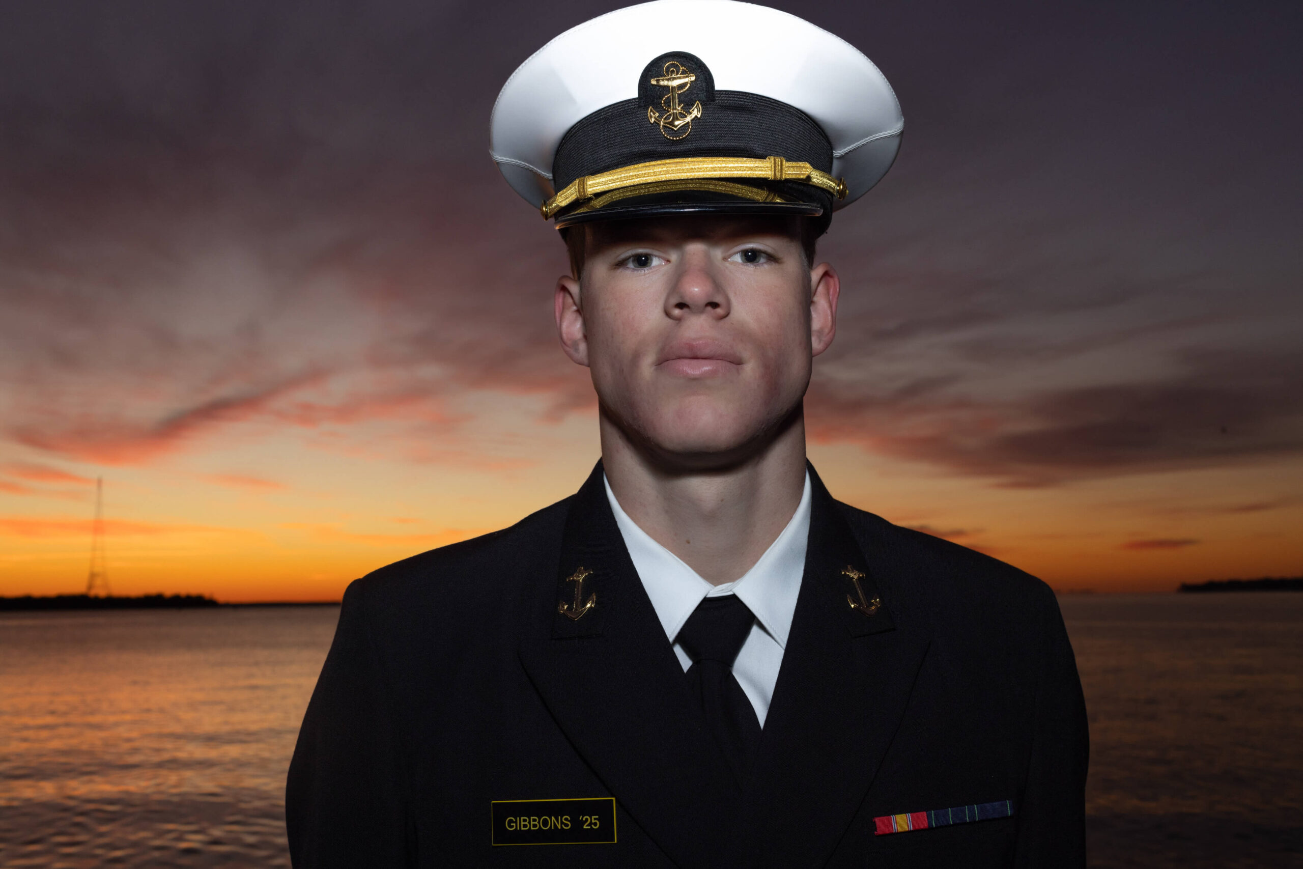 Dramatic sunrise on Chesapeake bay with USNA Midshipman in dress blue uniform.