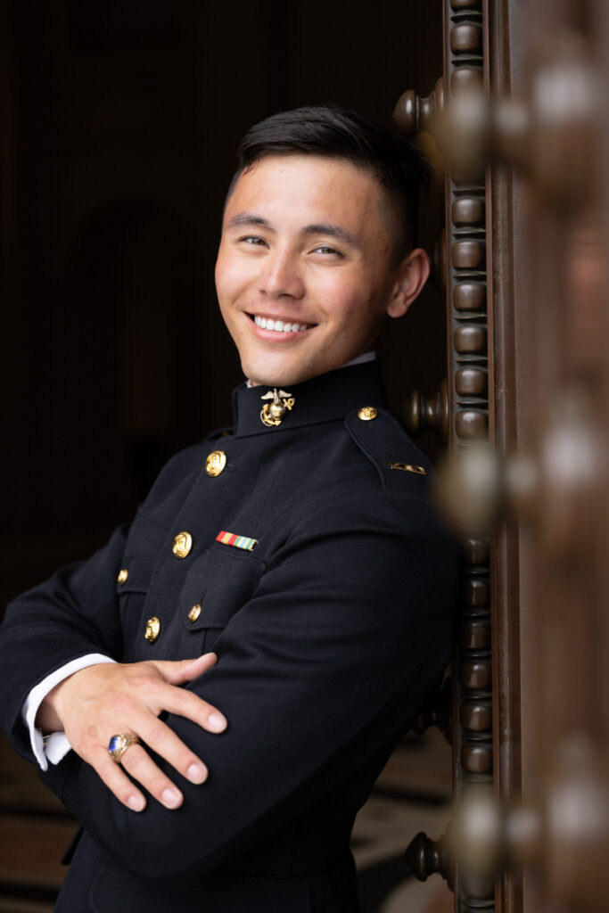 USNA Midshipman Marine in Uniform photoshoot at Bancroft Hall doors smiling with arms crossed. 